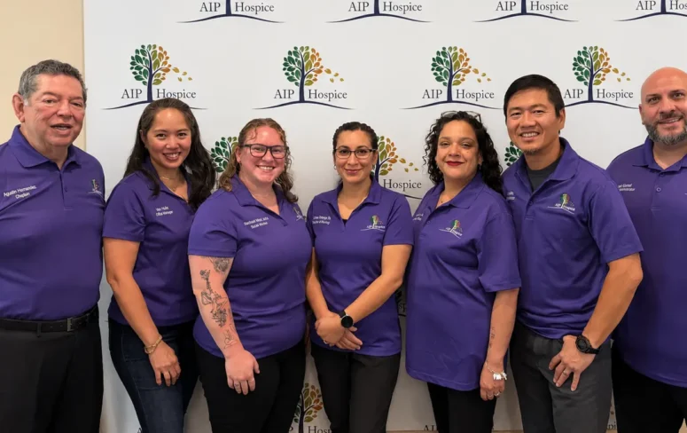Seven members of the AIP Hospice team standing together in purple uniforms.